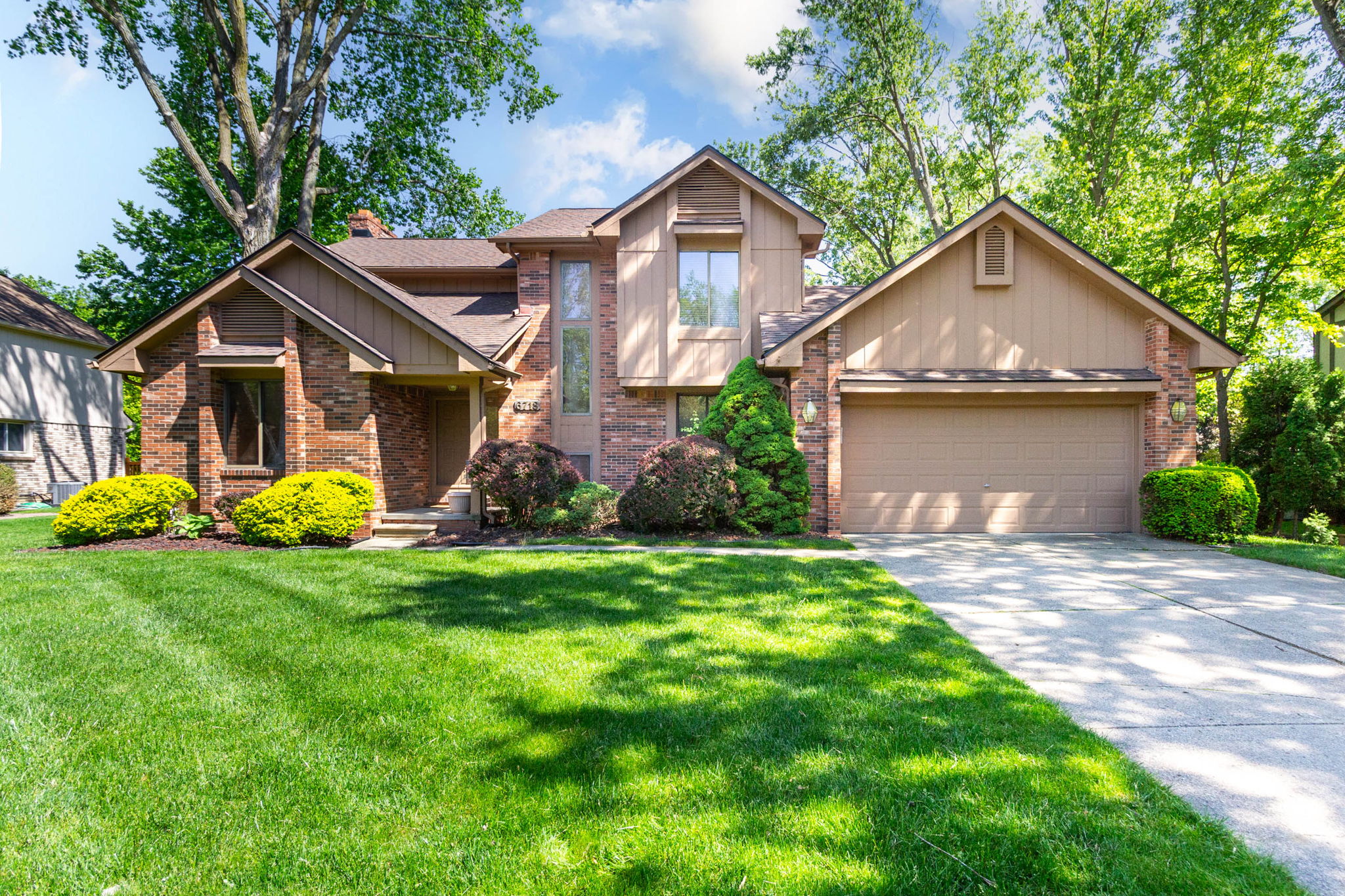 Front exterior of 6718 Forest Park Drive, Troy MI — two-story brick colonial on a private treed lot in Forest Creek subdivision