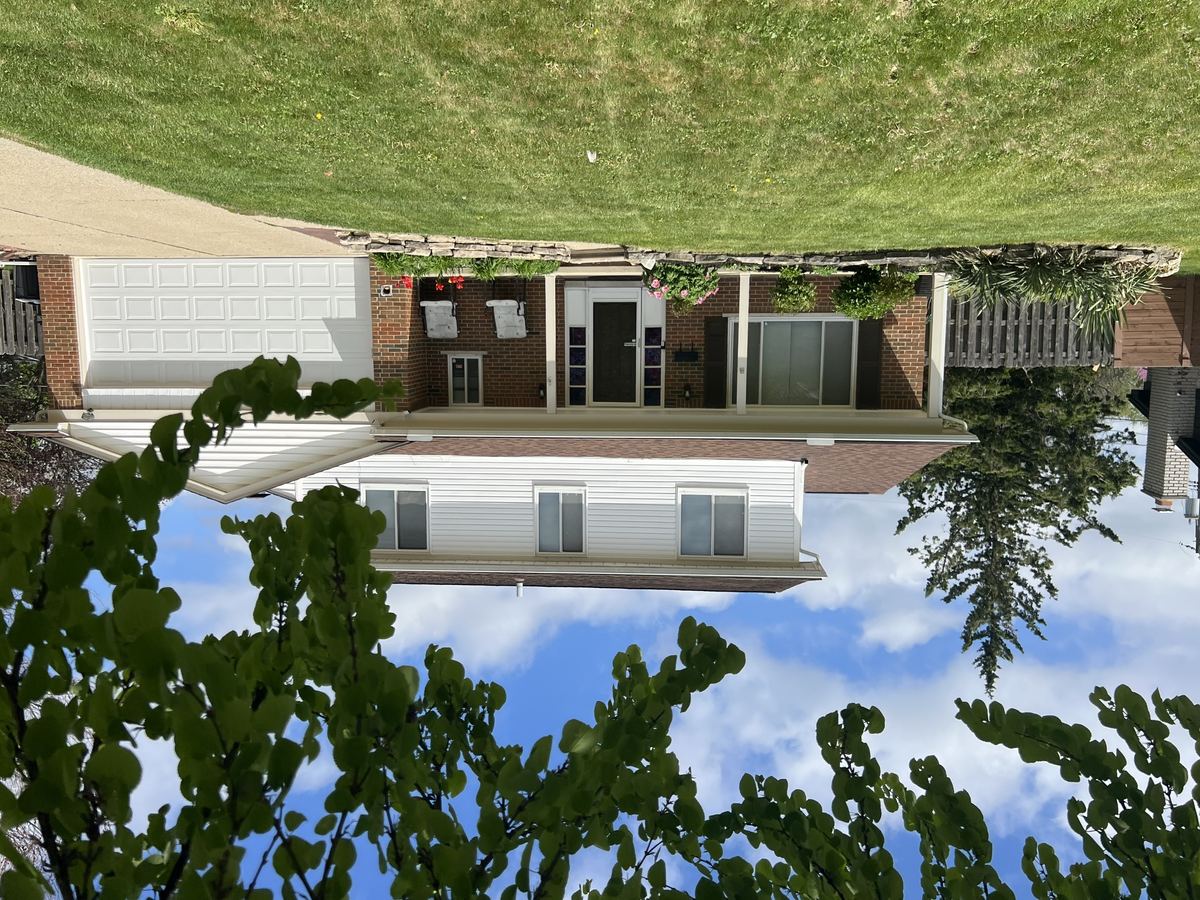Front exterior of 4033 Ramblewood Drive, Troy MI — two-story brick colonial with attached two-car garage and beautifully landscaped front yard